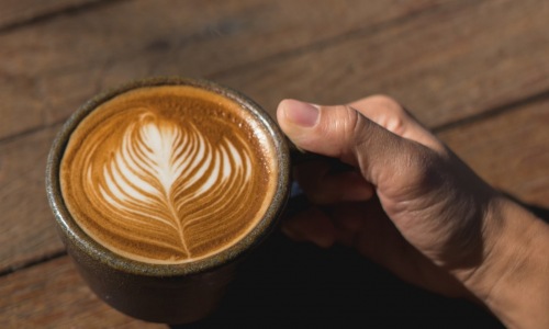 lifestyle image of a hand holding a mug of coffee