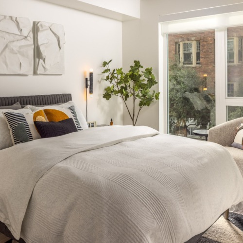 Contemporary apartment bedroom with large windows, neutral tones, and city views in San Francisco