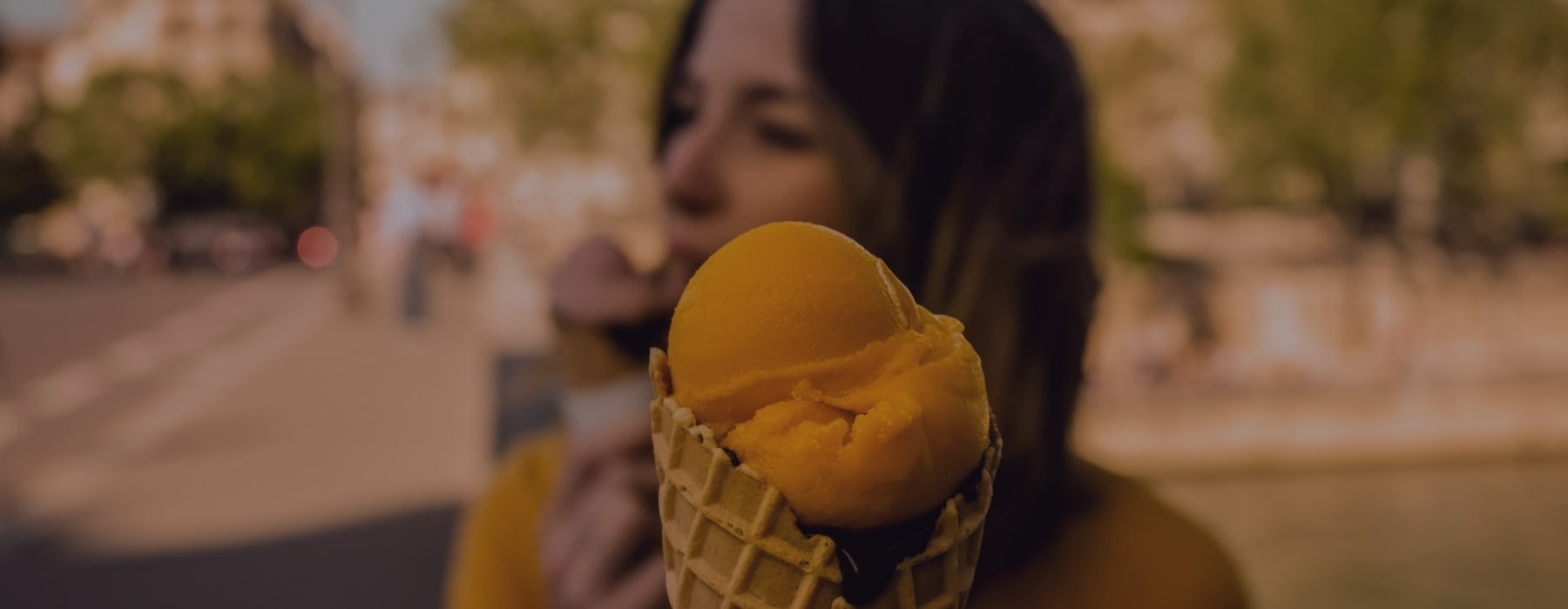 lifestyle of a close-up of ice cream with a girl in the background also eating ice cream